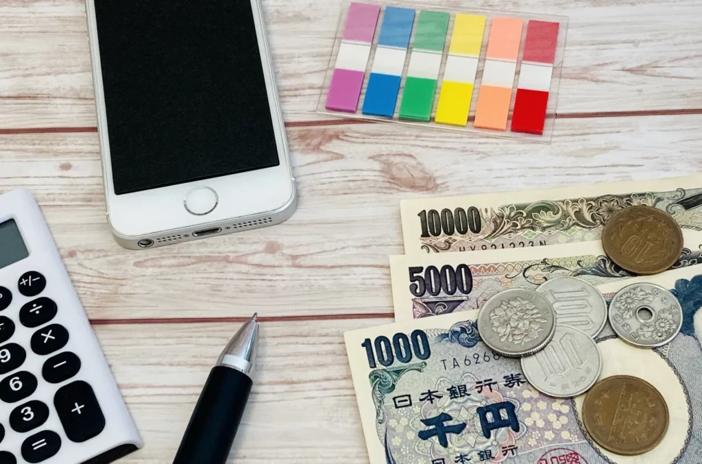 お金とスマホ・ボールペンが並ぶ